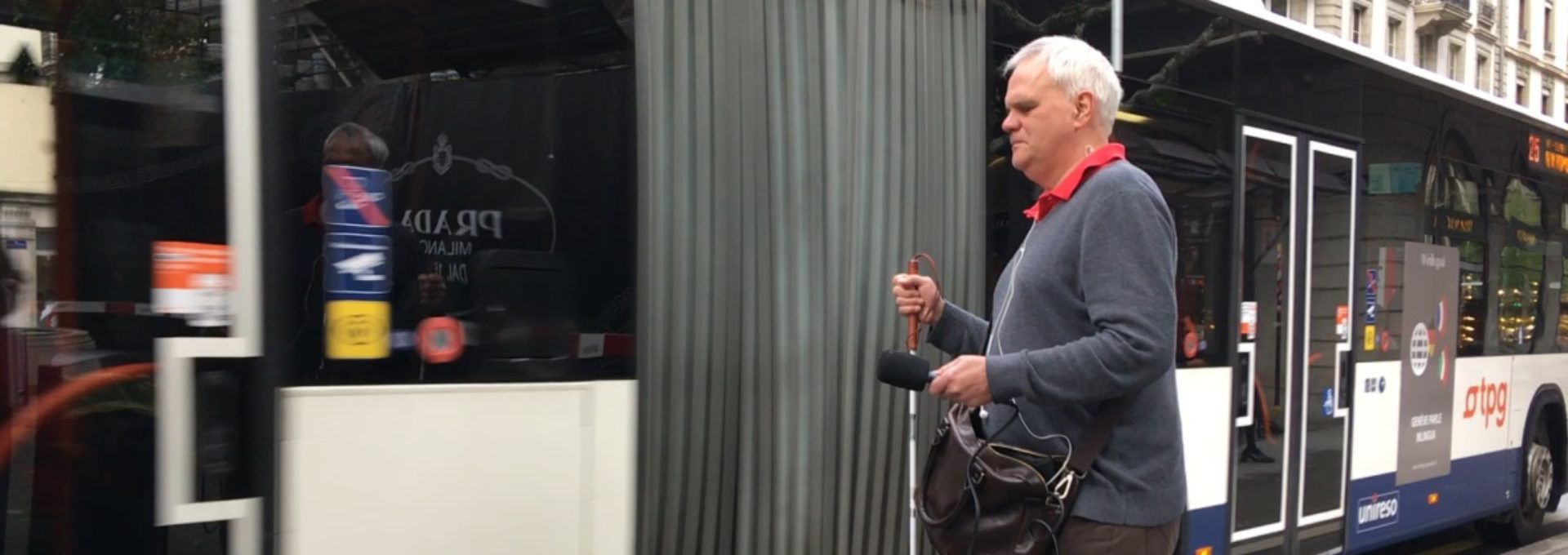 Photo: Jean-Marc Meyrat debout devant un bus TPG avec sa canne blanche.