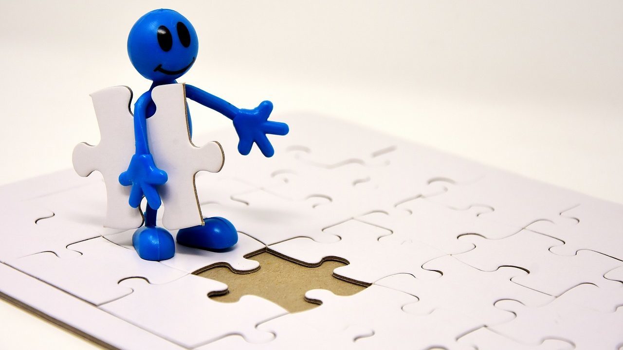 Photo: Bonhomme portant une pièce de puzzle pour compléter le plateau.