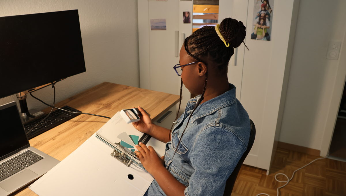 Photo de Rebecca, utilisant une loupe pour lire ses devoirs