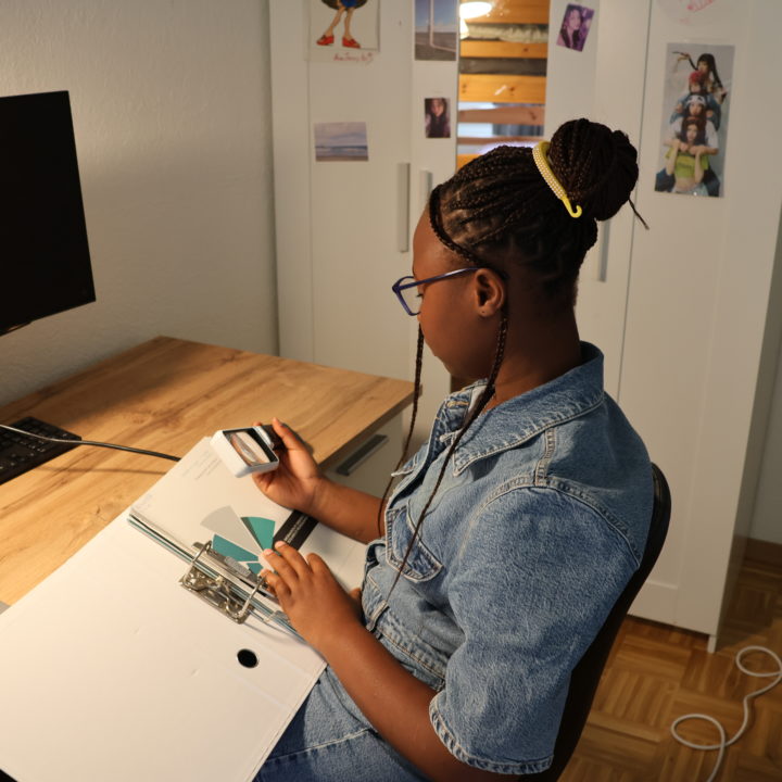 Photo de Rebecca, utilisant une loupe pour lire ses devoirs